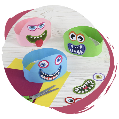 Drei verschiedenfarbige, selbstgebastelte Monster-Masken liegen auf dem Tisch